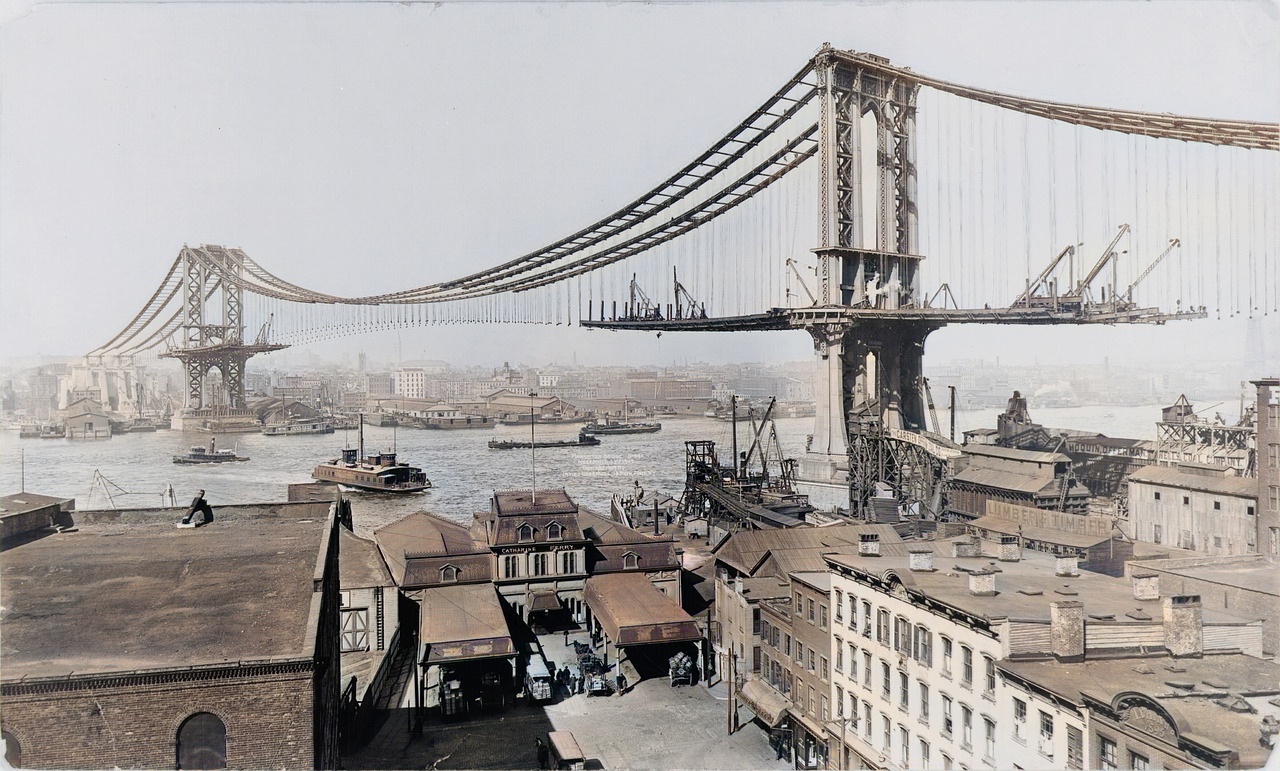 A colourised photograph of a suspension bridge under construction